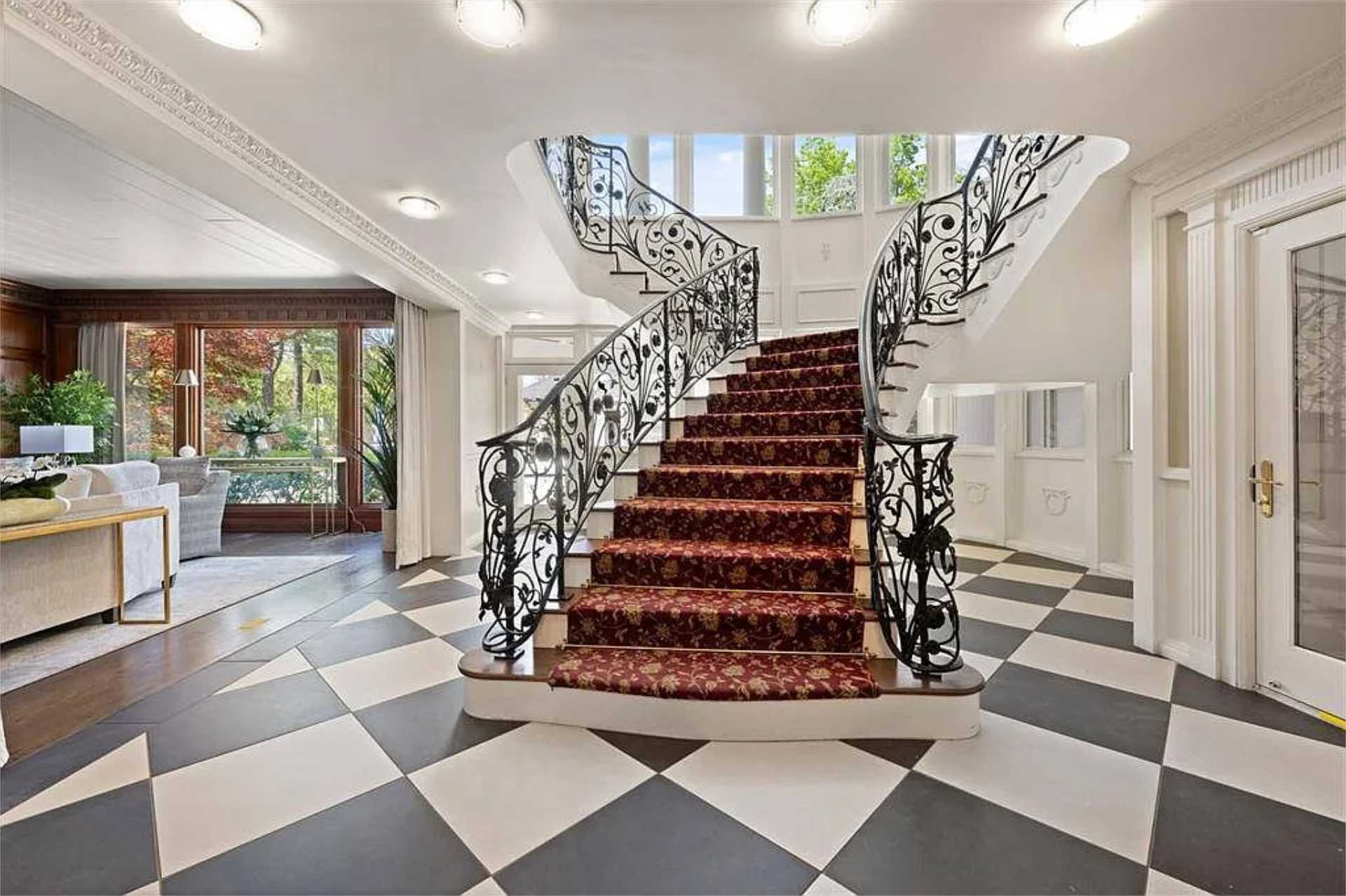 Sweeping wrought-iron staircase over checkered marble foyer