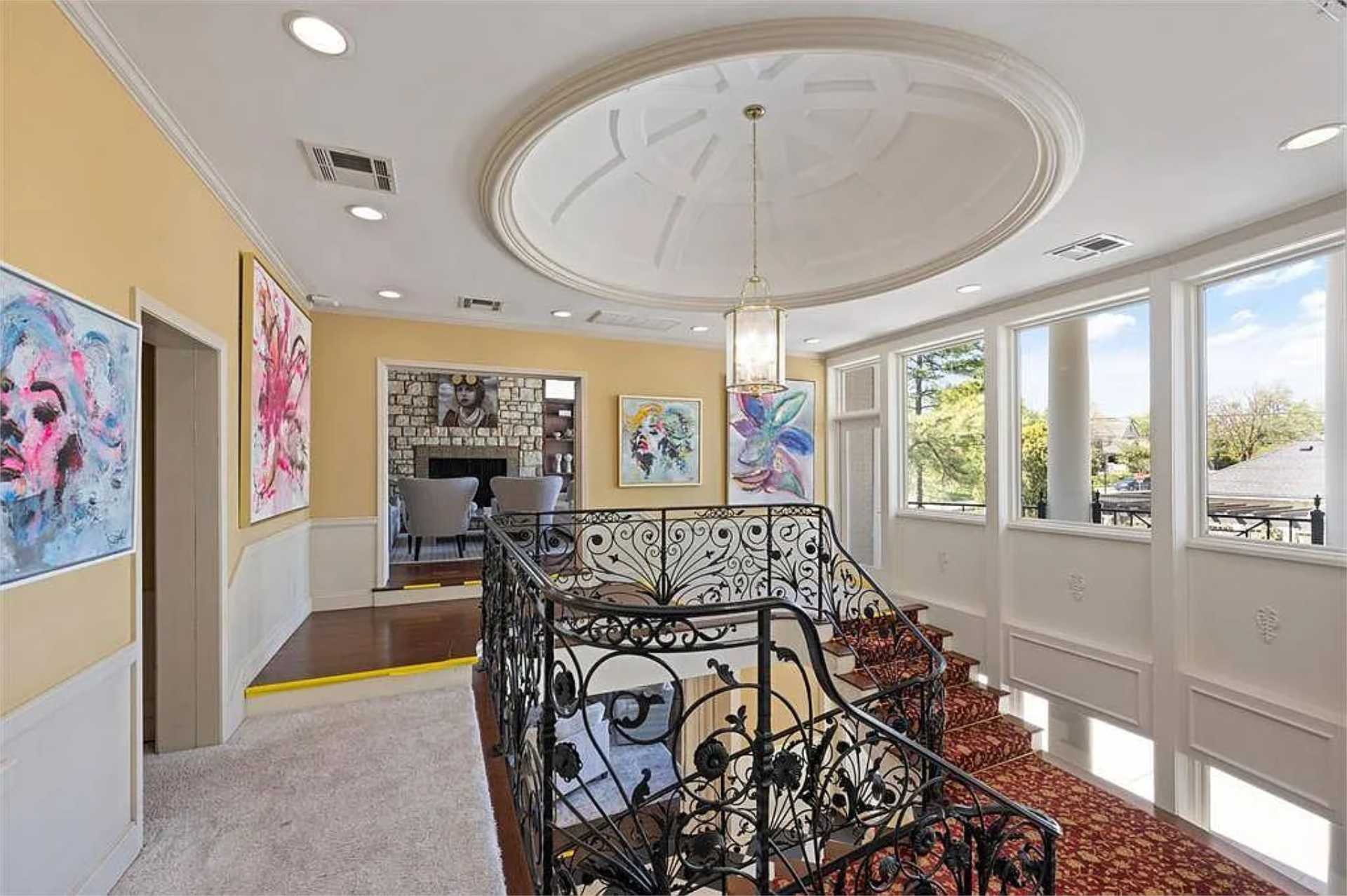 Domed upper landing with curated artwork and wrought-iron railing