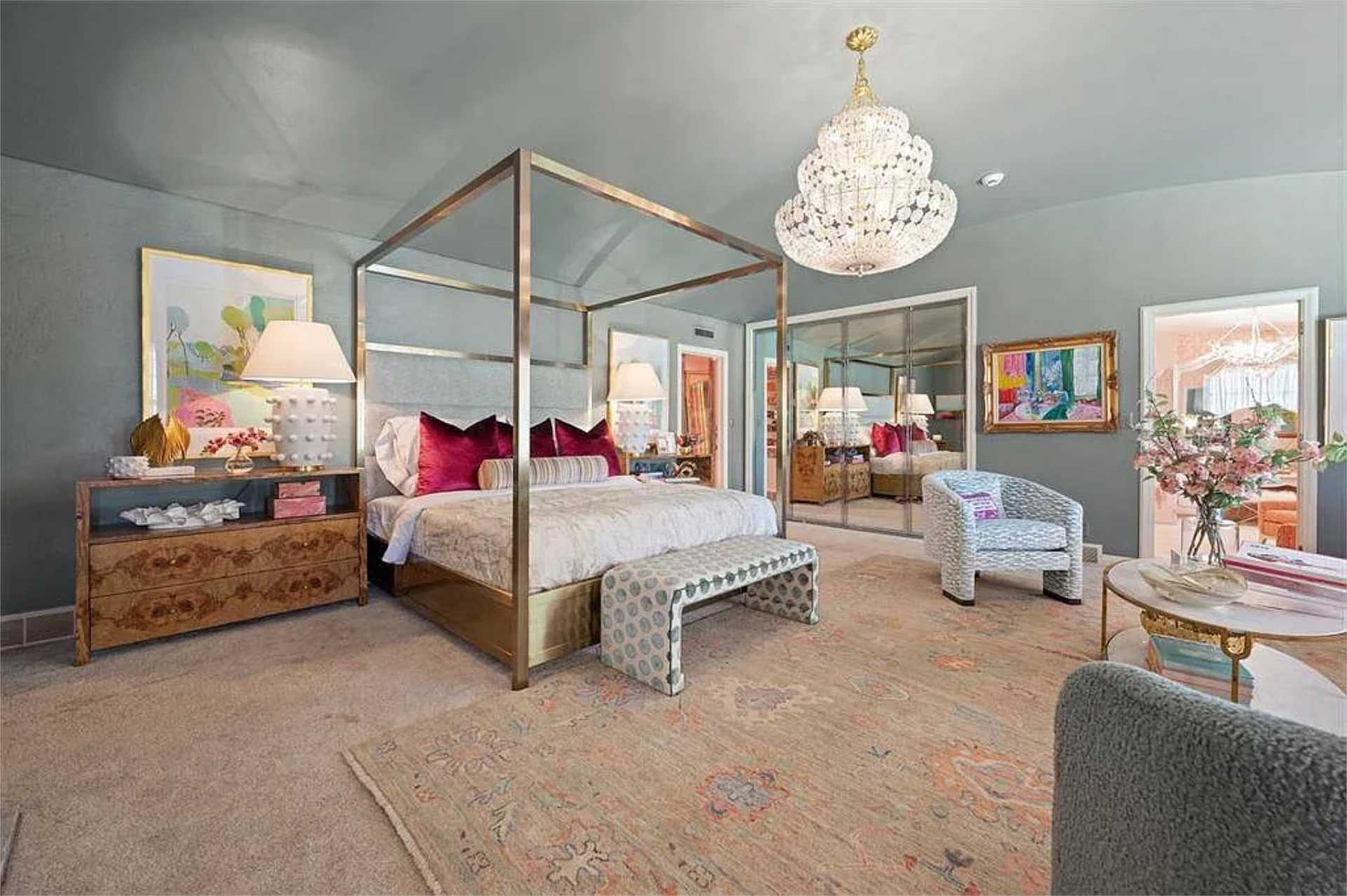 Primary bedroom suite with canopy bed and crystal chandelier